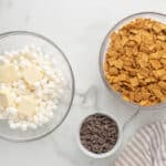 Bowls of Golden Grahams cereal, chocolate chunks, and mini marshmallows with added pats of butter.