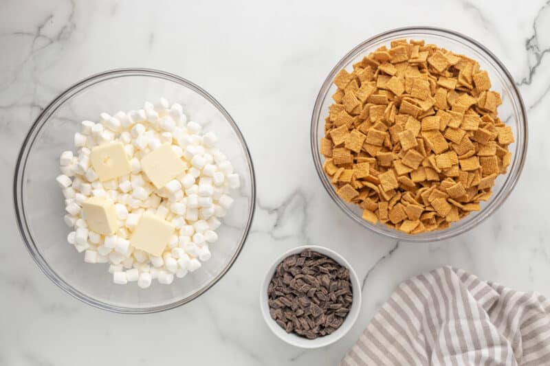 Bowls of Golden Grahams cereal, chocolate chunks, and mini marshmallows with added pats of butter.