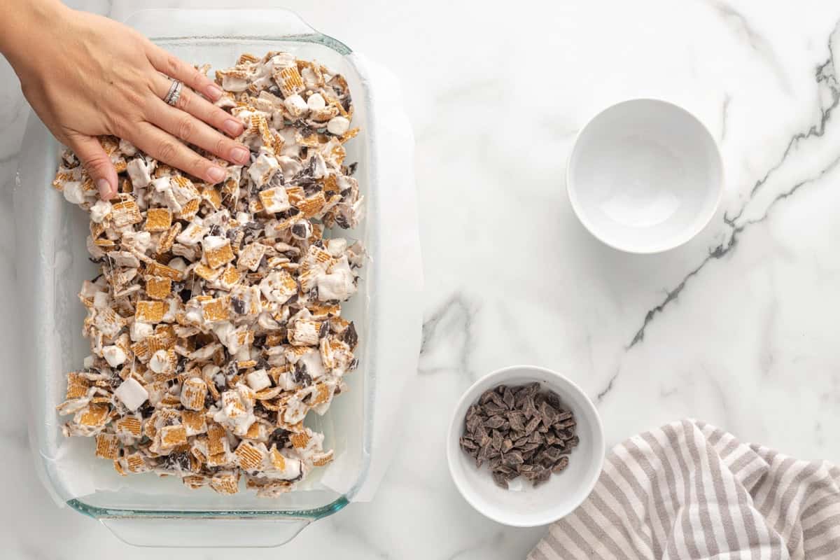Patting down Golden Grahams marshmallow mixture into baking dish.