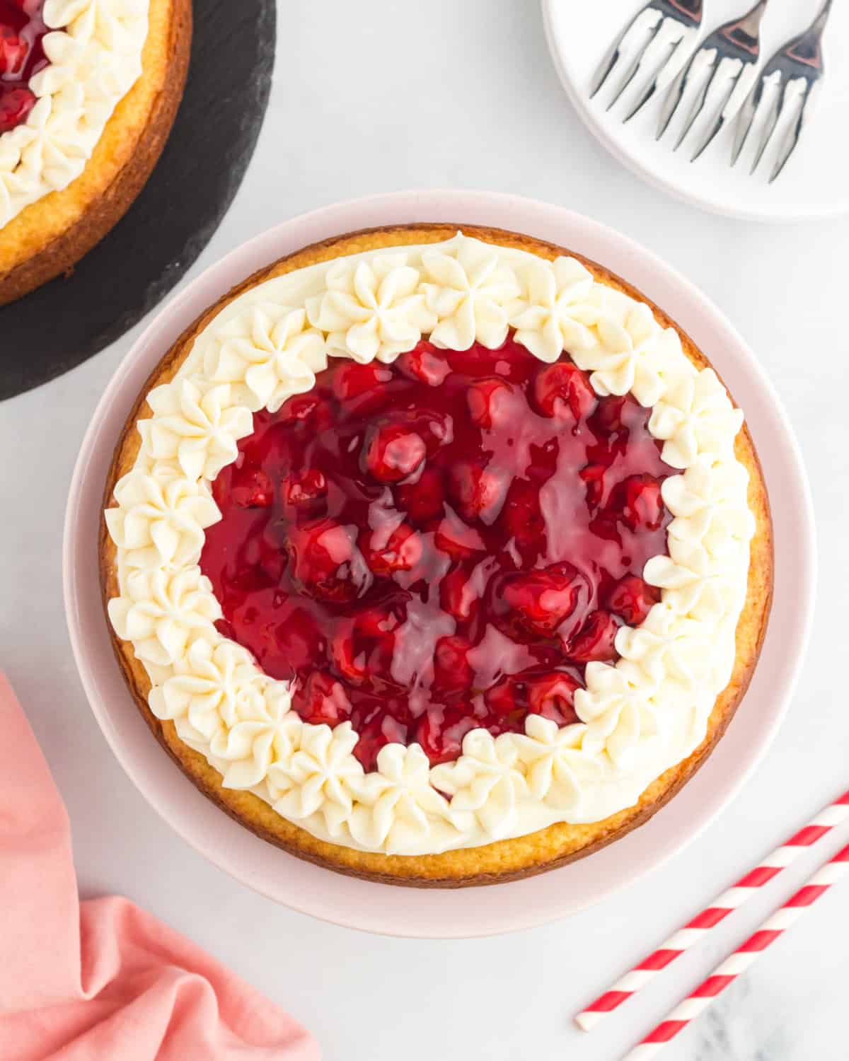 Cherry cheesecake cake topped with cream cheese frosting and cherry pie filling.