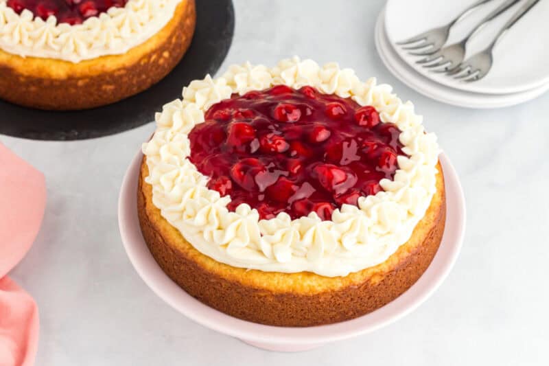 Cherry cheesecake cake topped with cream cheese frosting and cherry pie filling.