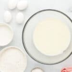 Beaten cream cheese, milk, and vegetable oil in a glass mixing bowl surrounded by ingredients.