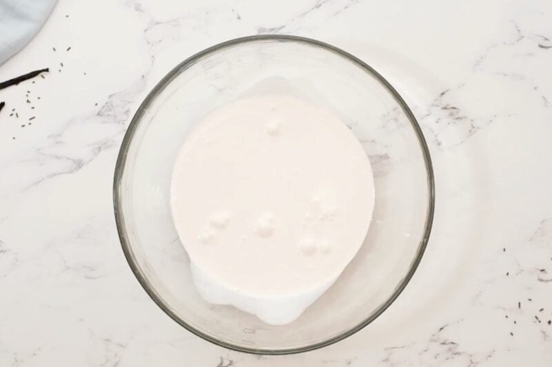 Heavy whipping cream in a glass mixing bowl.