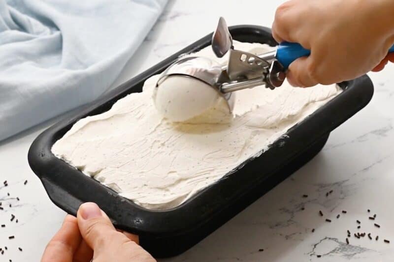 Scooping no churn vanilla ice cream out of a loaf pan.