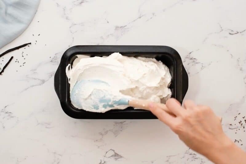 Using a rubber spatula to spread ice cream mixture into a loaf pan.