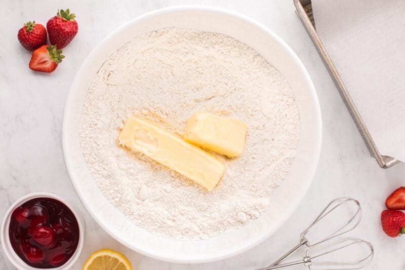 Sticks of butter added to a bowl of flour.
