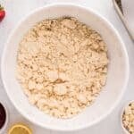 Beaten cake mix, all-purpose flour, and butter in a white mixing bowl surrounded by ingredients.