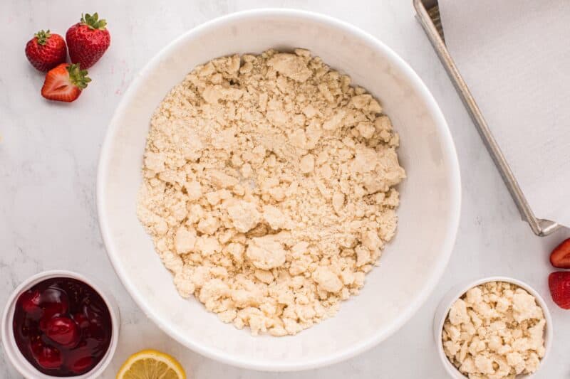 Beaten cake mix, all-purpose flour, and butter in a white mixing bowl surrounded by ingredients.