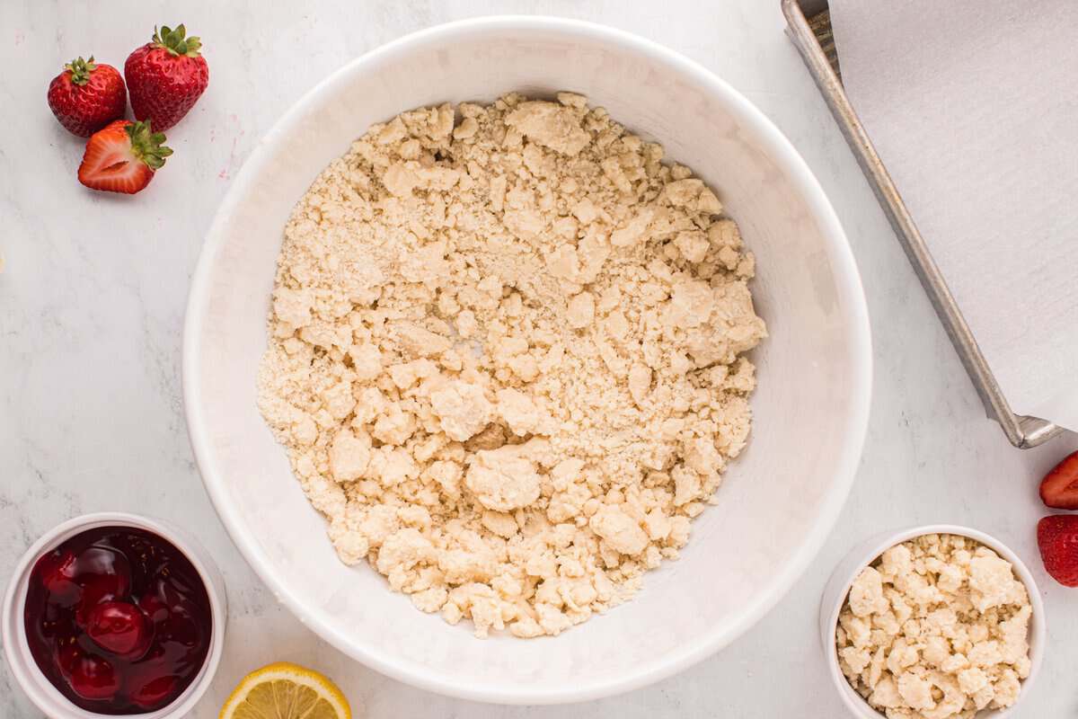 Beaten cake mix, all-purpose flour, and butter in a white mixing bowl surrounded by ingredients.