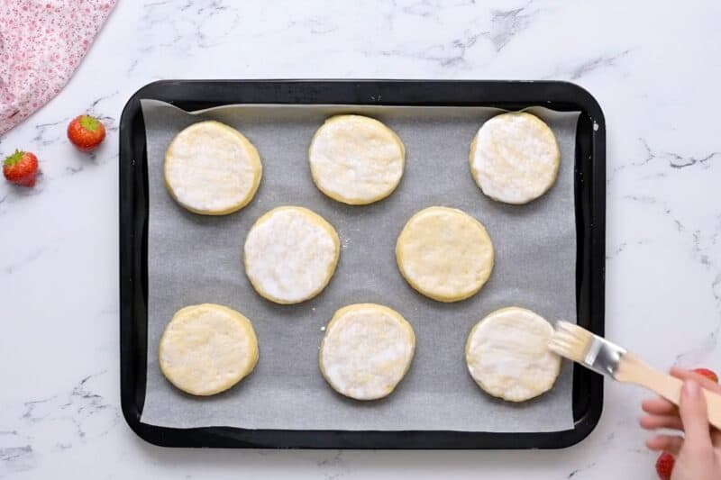 Brushing heavy cream onto biscuit dough.