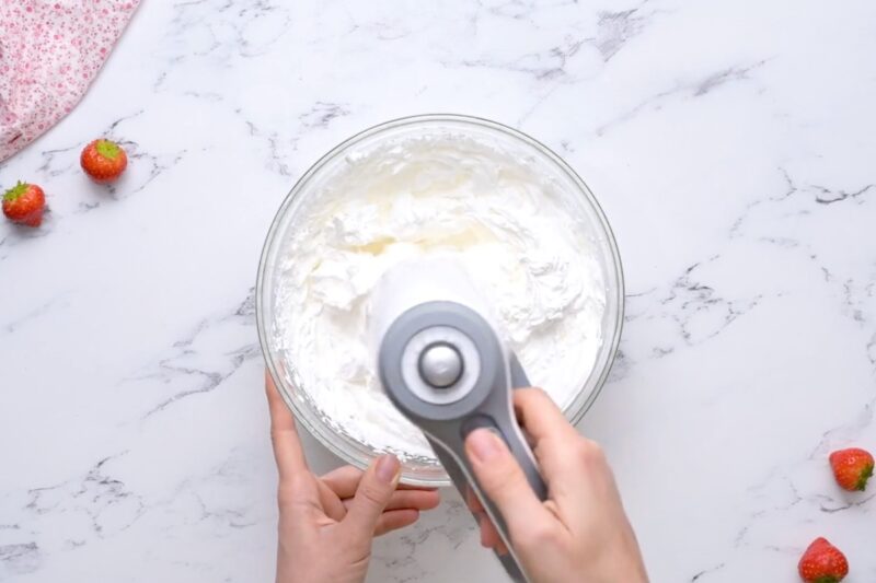 Whipping cream in a bowl, using a hand mixer.