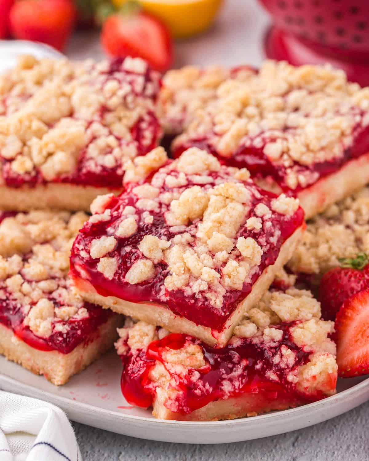 Stacked slices of strawberry crumble bars on a white plate.