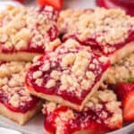 Stacked slices of strawberry crumble bars on a white plate.