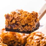 A spatula lifting a caramel cornflake brownie with layers of fudgy brownie, sweet caramel, and crunchy cornflakes.