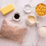 Ingredients for caramel cornflake brownies, featuring boxed brownie mix, granulated sugar, heavy whipping cream, unsalted butter, cornflakes, vanilla, and salt.