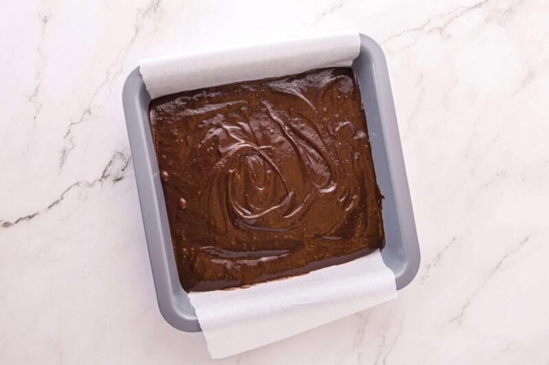 Brownie batter spread into a 9x9 baking dish.