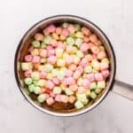 Rainbow marshmallows added to a saucepan with peanut butter mixture.