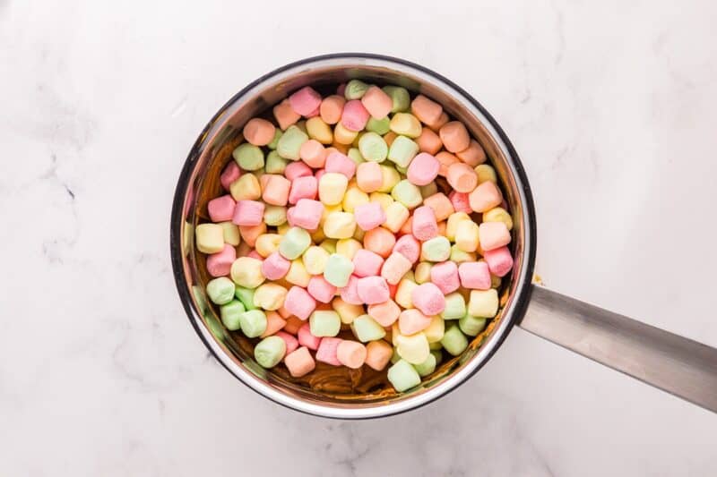 Rainbow marshmallows added to a saucepan with peanut butter mixture.