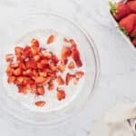 Fresh chopped strawberries added to a bowl of dry ingredients.