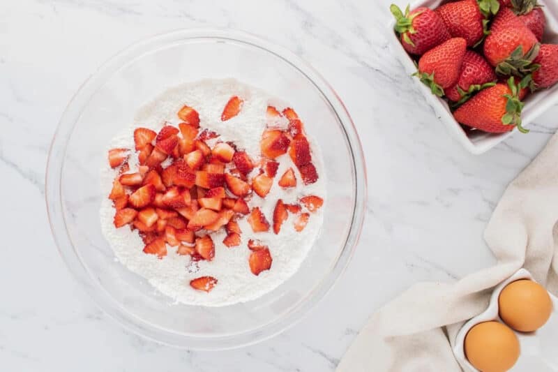 Fresh chopped strawberries added to a bowl of dry ingredients.