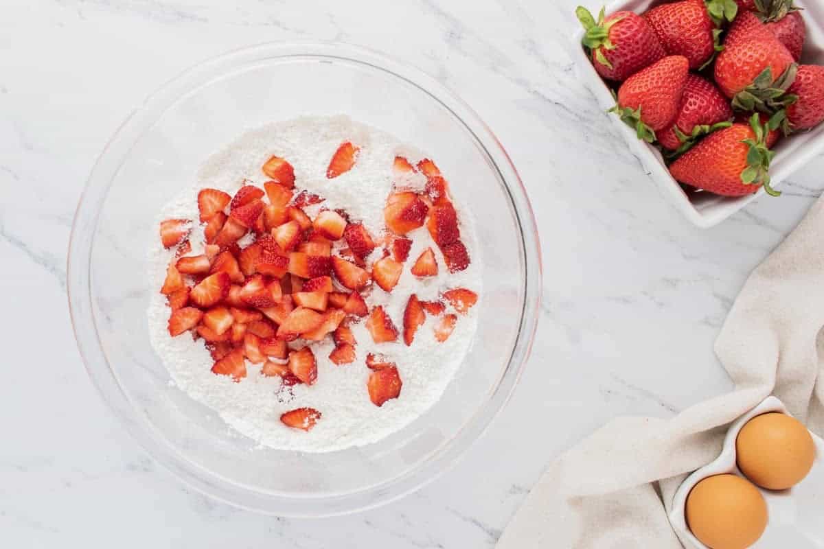 Fresh chopped strawberries added to a bowl of dry ingredients.