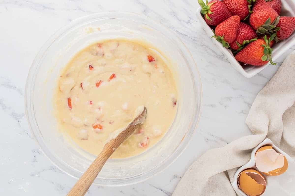 Strawberry muffin batter in a glass mixing bowl.