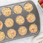 Muffin batter topped with streusel, in a muffin tin.