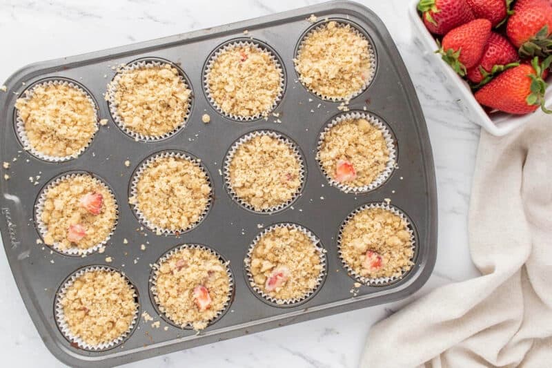 Muffin batter topped with streusel, in a muffin tin.
