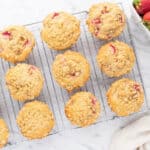 Baked strawberry muffins lined up on a cooling rack.