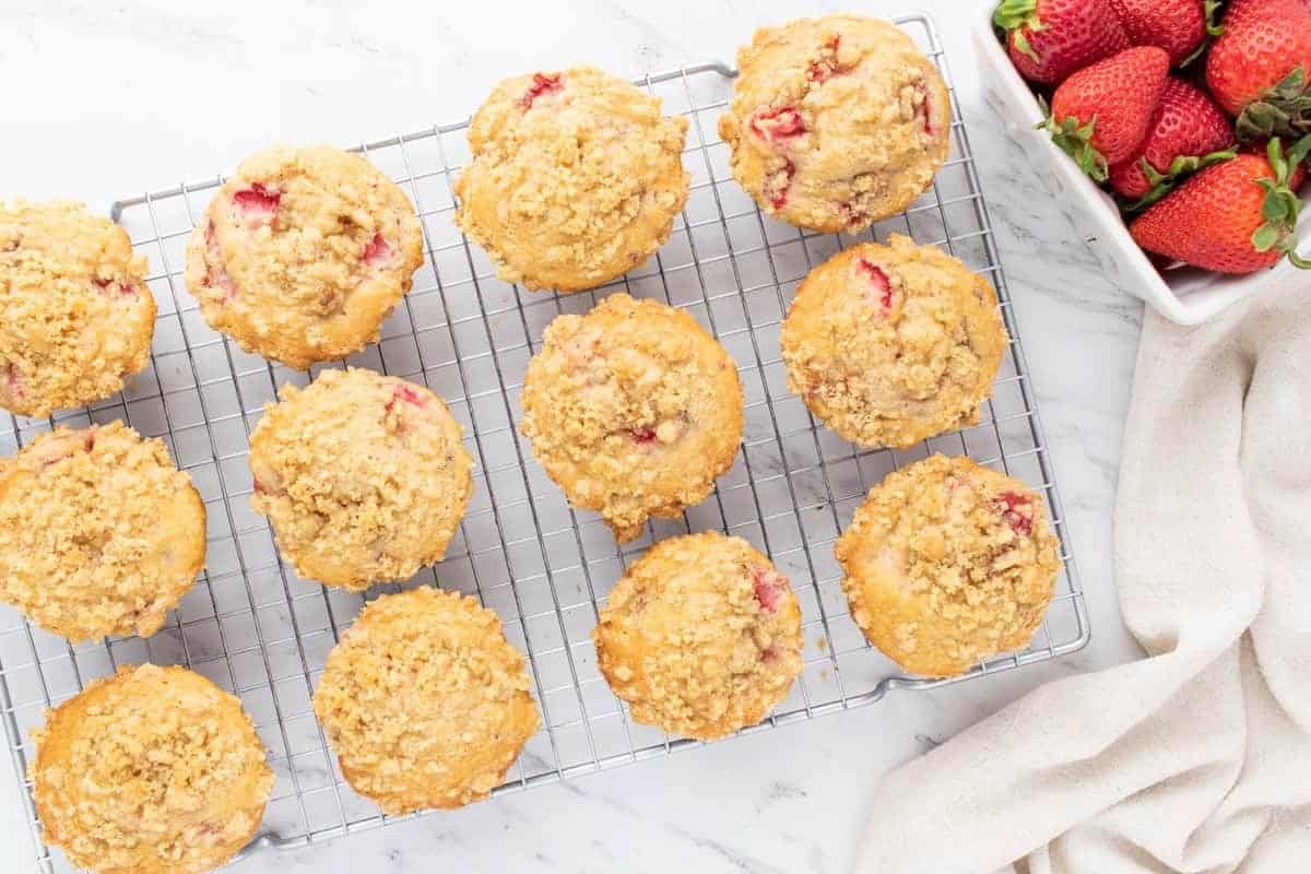 Baked strawberry muffins lined up on a cooling rack.