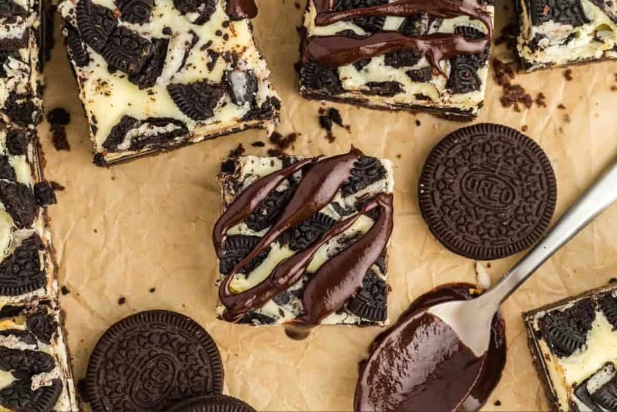 An Oreo cheesecake bar drizzled with chocolate ganache.