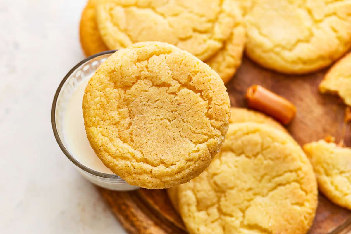 Caramel snickerdoodles with one cookie over a glass of milk.