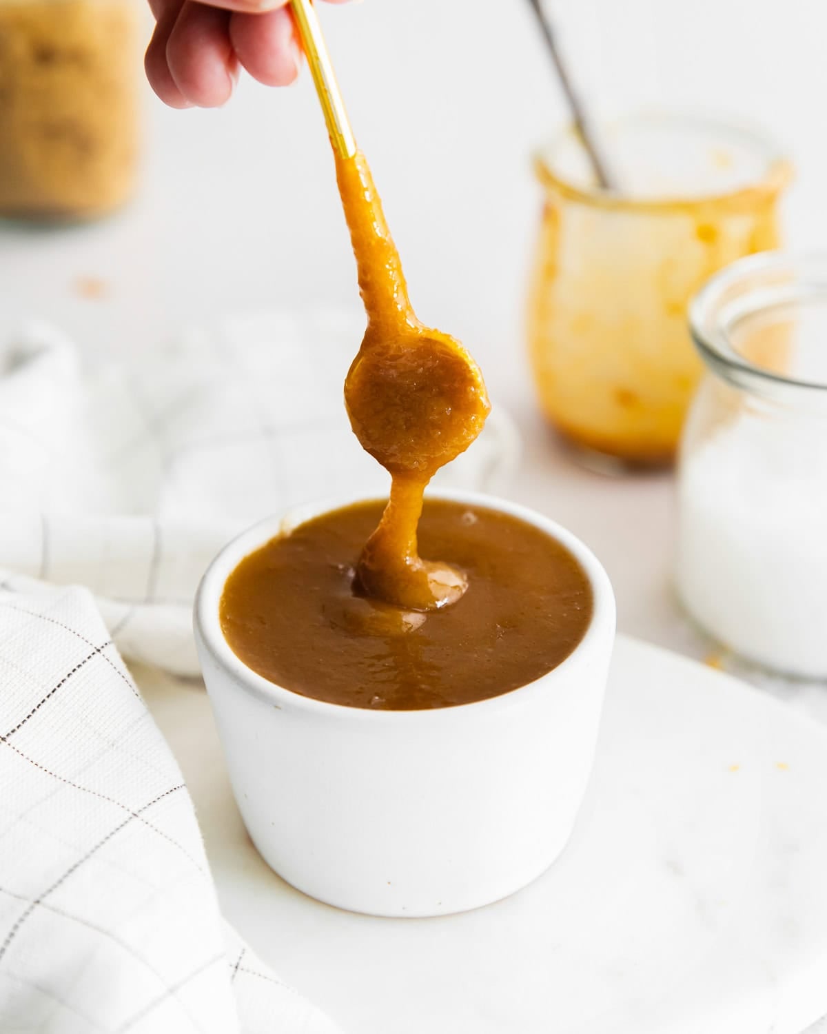 Dipping a spoon into a bowl of caramel sauce.
