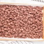 Brownie batter puppy chow spread out on a baking sheet.