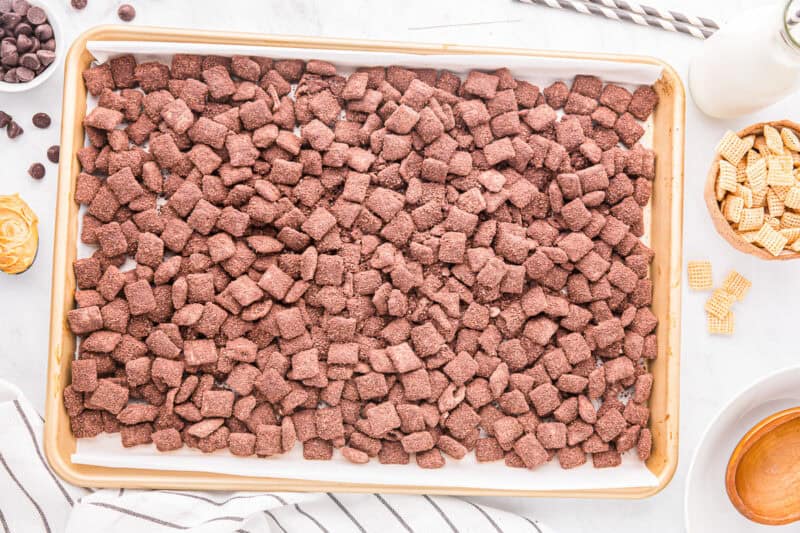 Brownie batter puppy chow spread out on a baking sheet.