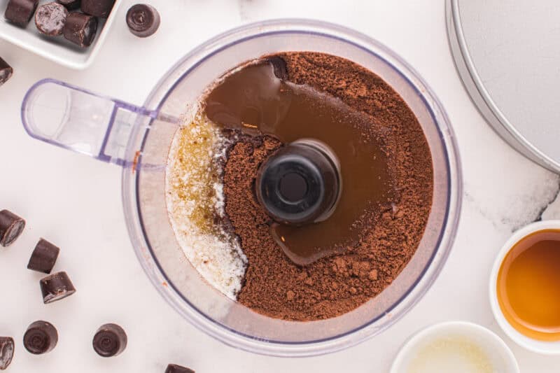 Chocolate Teddy graham cheesecake crust ingredients in a food processor.