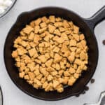Crushed graham crackers spread out in the bottom of a cast iron skillet.