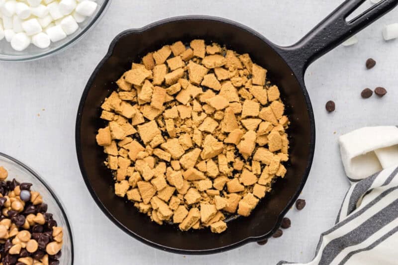 Crushed graham crackers spread out in the bottom of a cast iron skillet.