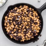 Peanut butter chips and chocolate chips layered into a cast iron skillet.