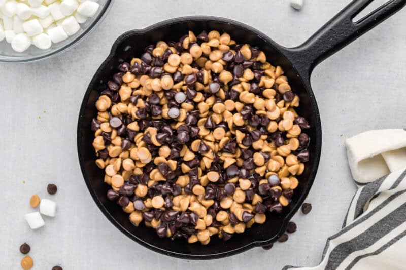 Peanut butter chips and chocolate chips layered into a cast iron skillet.