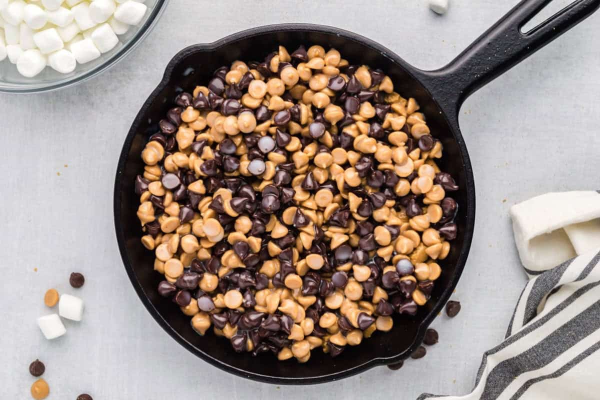 Peanut butter chips and chocolate chips layered into a cast iron skillet.