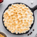 Baked s'mores dip in a cast iron skillet with browned marshmallow topping.