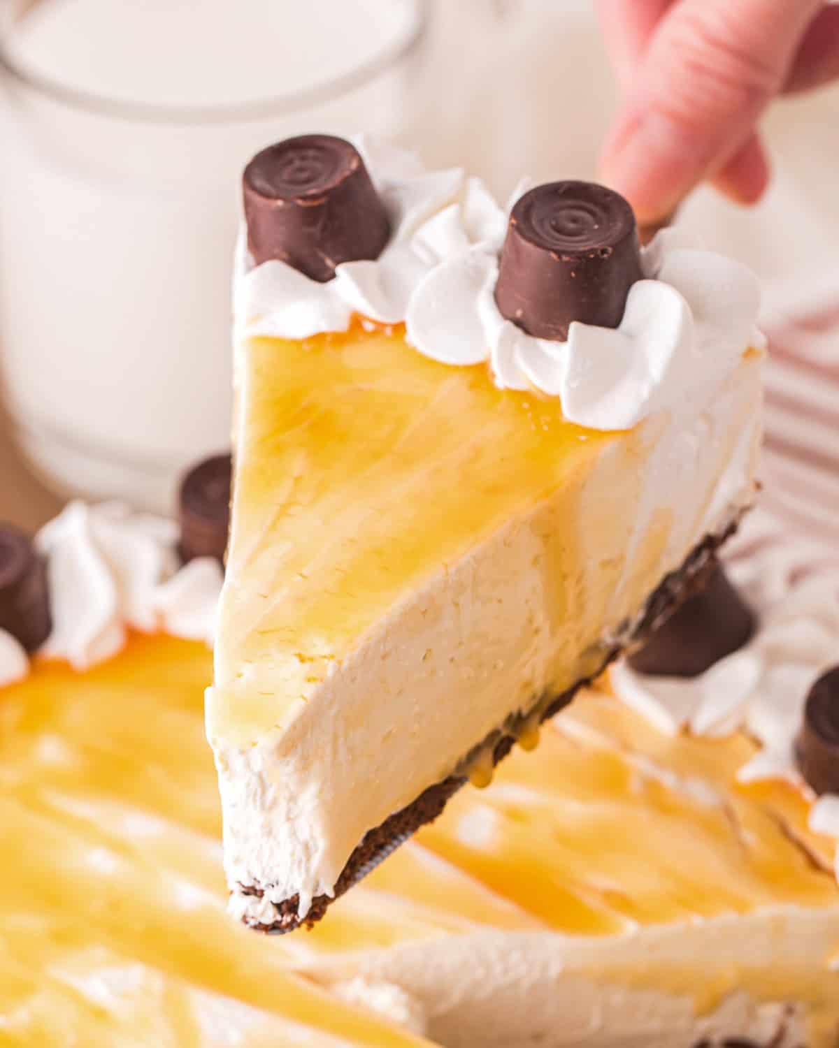 Holding up a slice of no bake cheesecake with caramel and Rolo candies.