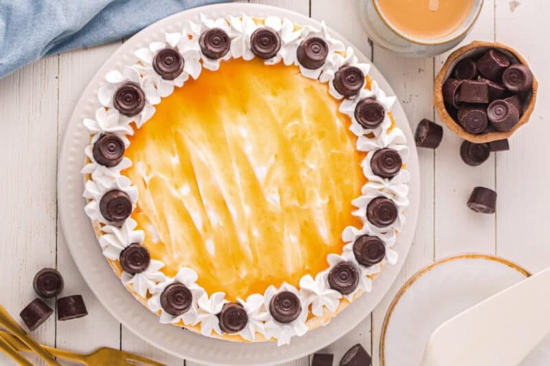 Completed Rolo cheesecake topped with whipped topping, caramel, and Rolo candies.