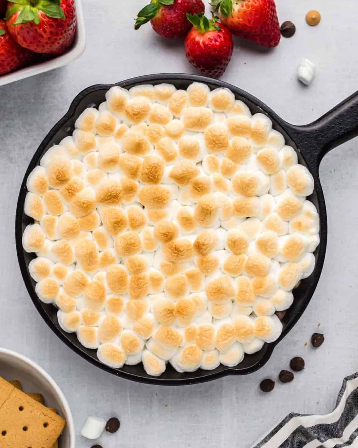 Oven-baked marshmallow s'mores dip on a counter top.