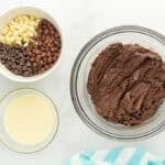 Chocolate cake batter in a bowl, next to a bowl of chocolate chips.