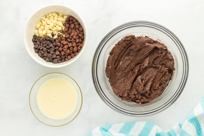Chocolate cake batter in a bowl, next to a bowl of chocolate chips.