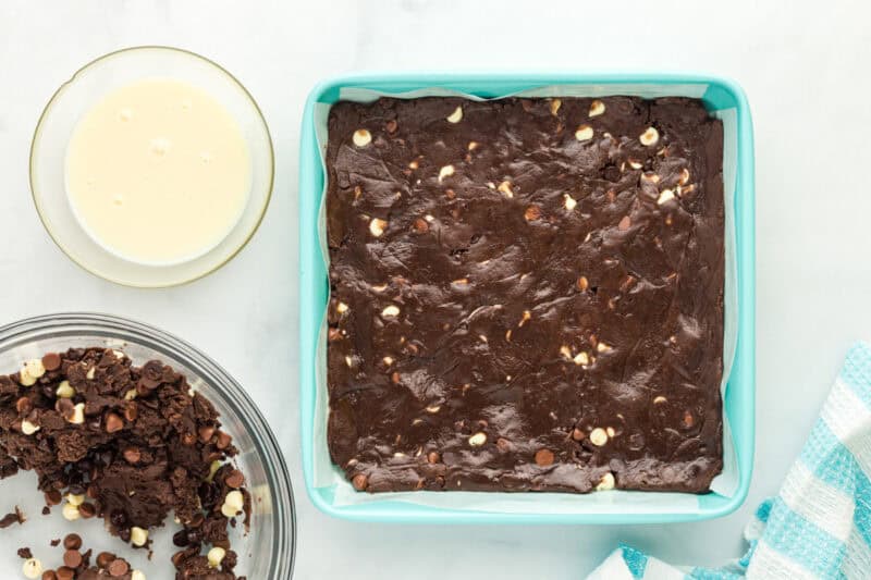 Chocolate brownie bar batter smoothed into a square baking pan.