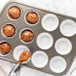 Spooning chocolate batter into cupcake tin.